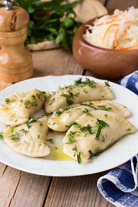 斯拉夫菜传统菜。木制的桌子上的白板上的马铃薯填充 varenyky