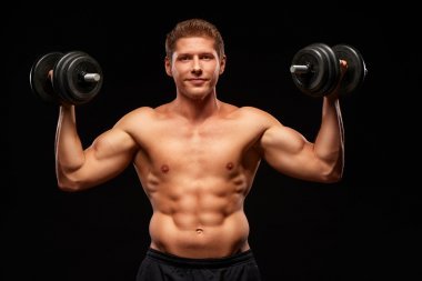 滿意的運(yùn)動(dòng)員微笑著手拿啞鈴孤立在黑色上