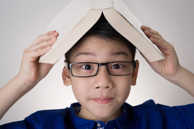 亞洲男孩頭思考的書照片