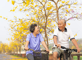 幸福的亚洲高级夫妇骑着自行车在公园