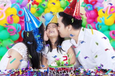 在生日聚会上亲吻他们的孩子的父母 在生日聚会上亲吻他们的孩子的父母
