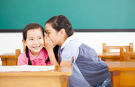 小女孩耳语和分享在教室里的秘密