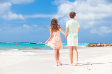 后視圖的快樂對年輕夫婦在沙灘上