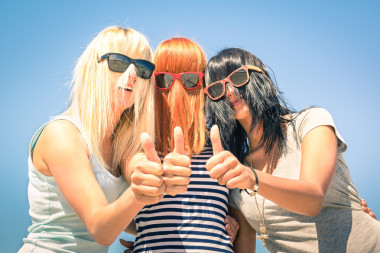 Groups of young girlfriends focus on colorful funny hair and sunglasses - summer expressions of friendship and fun with thumbs of positivity -- best friends sharing the concept of happiness together
