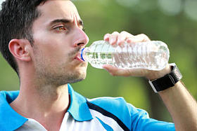 在中断运行后饮用矿泉水的运动型男性转轮