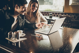 两人在酒吧使用一台笔记本电脑