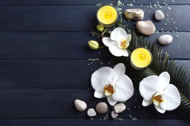 靜物與綻放美麗的蘭花花、 蠟燭和木制背景上的卵石