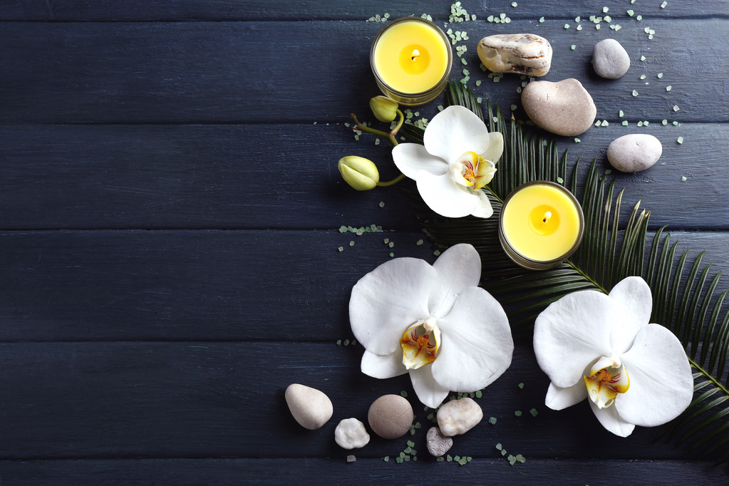 静物与绽放美丽的兰花花、 蜡烛和木制背景上的卵石