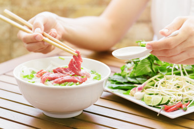 年輕女子在越南的街頭咖啡館吃 Pho 