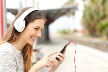 十幾歲的女孩與等待一列火車(chē)的耳機(jī)聽(tīng)音樂(lè)