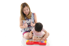 可爱的母亲教她的儿子小孩玩电动玩具钢琴