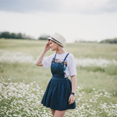 美麗的年輕女子的牛仔褲裙子和甘菊領(lǐng)域構(gòu)成的那頂草帽