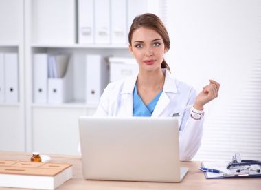 美麗年輕微笑的女醫(yī)生坐在辦公桌前和寫作