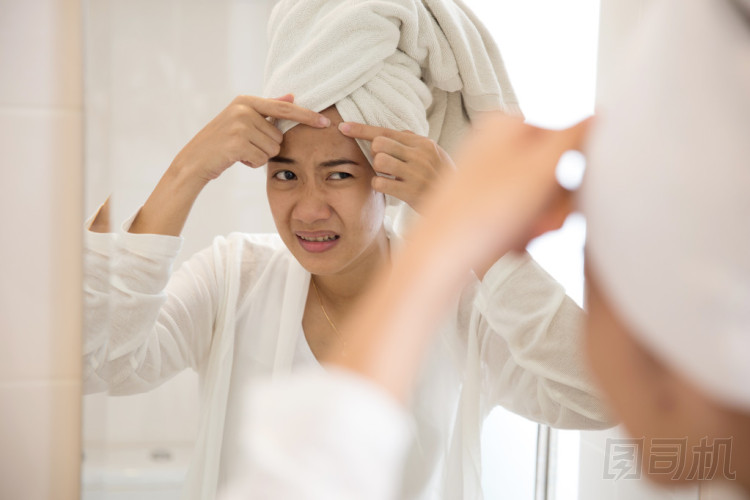 亞洲女人在她的額頭上按痤瘡