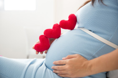 亞洲年輕孕婦把心形狀配件在她