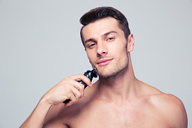 英俊的男人用电动剃须刀剃须图片