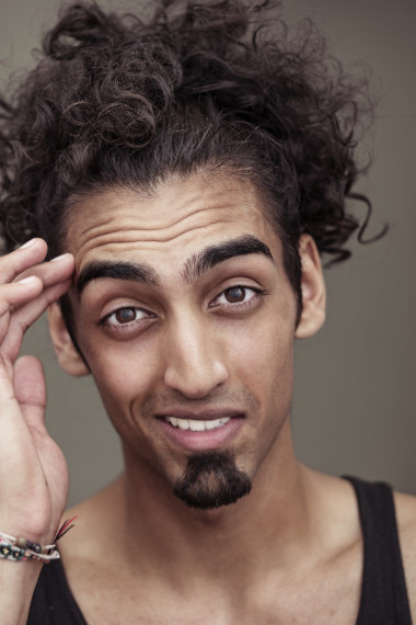 卷曲長(zhǎng)發(fā)的年輕男子，對(duì)著鏡頭微笑