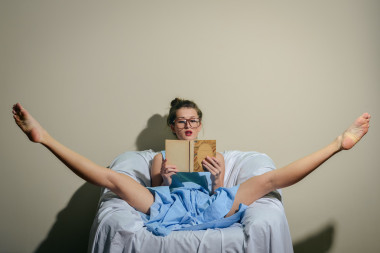 年輕的女士穿著藍色的衣服戴著眼鏡拿著一本書