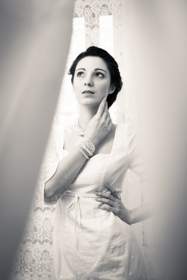 年轻的女士，穿白色连衣裙躲在薄纱窗帘