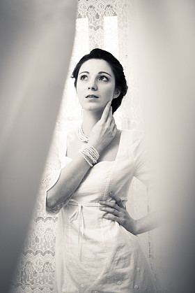 年轻的女士，穿白色连衣裙躲在薄纱窗帘