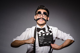 假胡子持有 clapperboard 上孤立的年轻男人