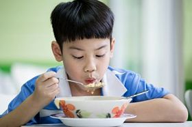年轻的中国男孩，坐在家里吃顿饭