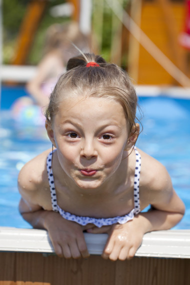 儿童在游泳池附近的蓝色比基尼的女孩。炎热的夏天