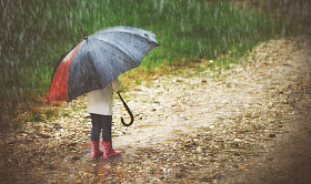 快乐的小女孩撑着伞在雨中奔跑