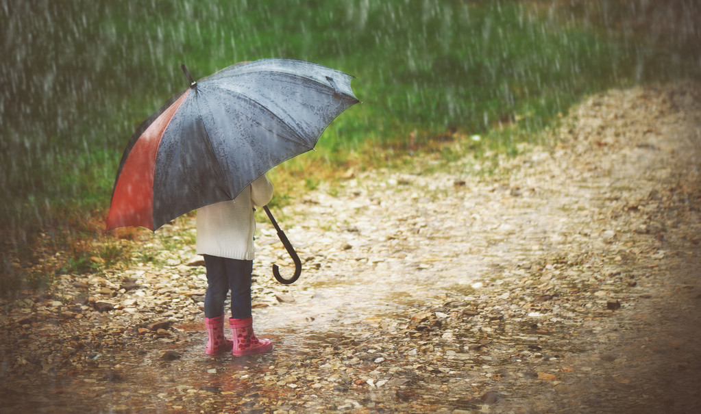 快乐的小女孩撑着伞在雨中奔跑
