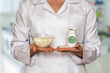 年轻的医生拿着凝乳和一瓶维生素片比较它们