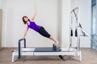 健身房女人彼拉多教練在爐床上伸展