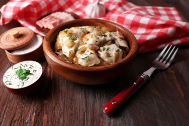 油炸的餃子用洋蔥和培根在煎鍋上木桌背景