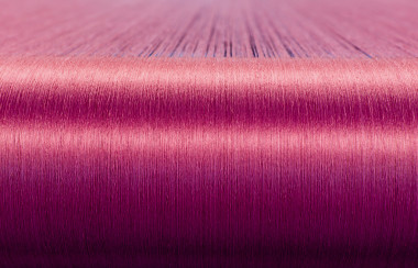 在一家紡織廠翹曲織機上的綠色絲綢  