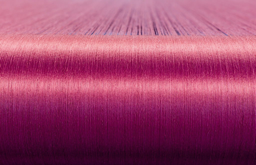 在一家纺织厂翘曲织机上的绿色丝绸  