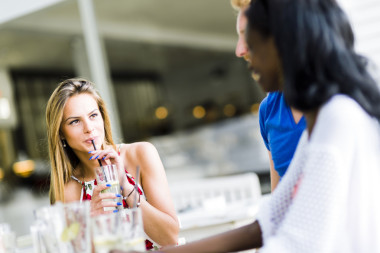 美麗的女人喝著通過一根稻草