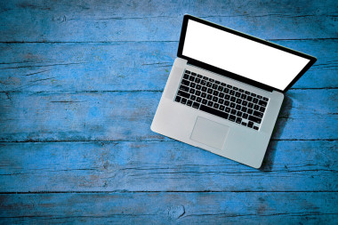 白色的空白屏幕，在藍(lán)色的木板上作為紋理的筆記本電腦 