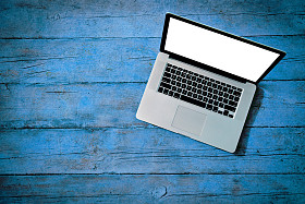 白色的空白屏幕，在蓝色的木板上作为纹理的笔记本电脑 