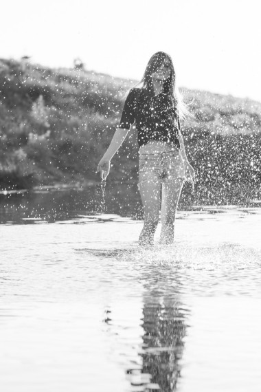 构成和玩水的一条小河的长长的直头发的漂亮女孩。黑色和白色，艺术摄影