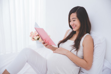 美麗亞洲孕婦閱讀筆記書(shū)，微笑