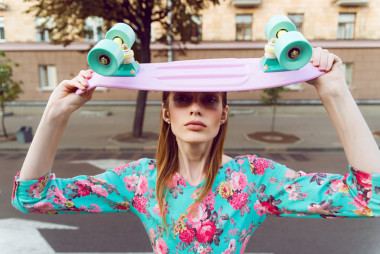 美麗和時尚的年輕女子和一個滑板在城市街道上的合影