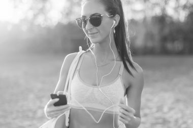 黑人和白人女运动员听音乐看着智能手机后在大自然户外肖像夏夜