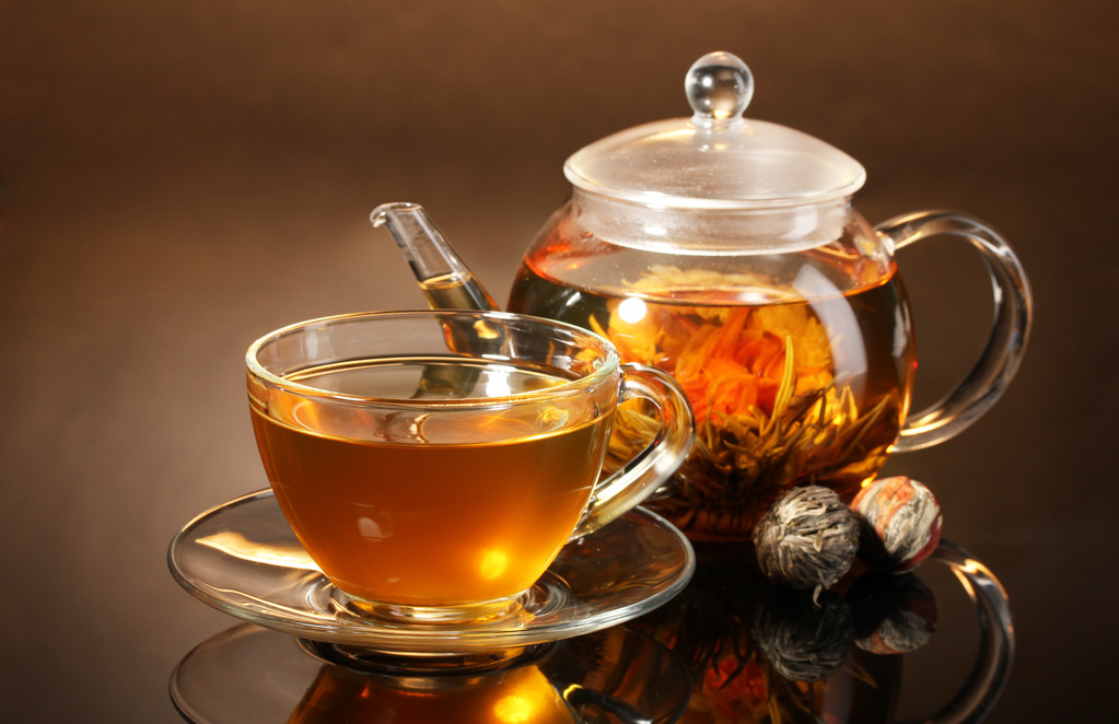 玻璃茶壶和异国情调绿茶棕色 backgro 上的木桌上的杯子