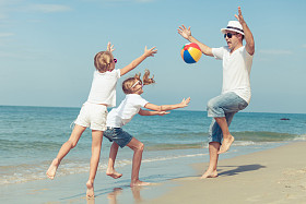 父亲和女儿在日落的时候在海滩上玩. 