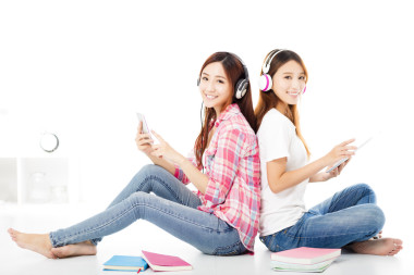 坐在地板上的兩個快樂的青少年學(xué)生女孩