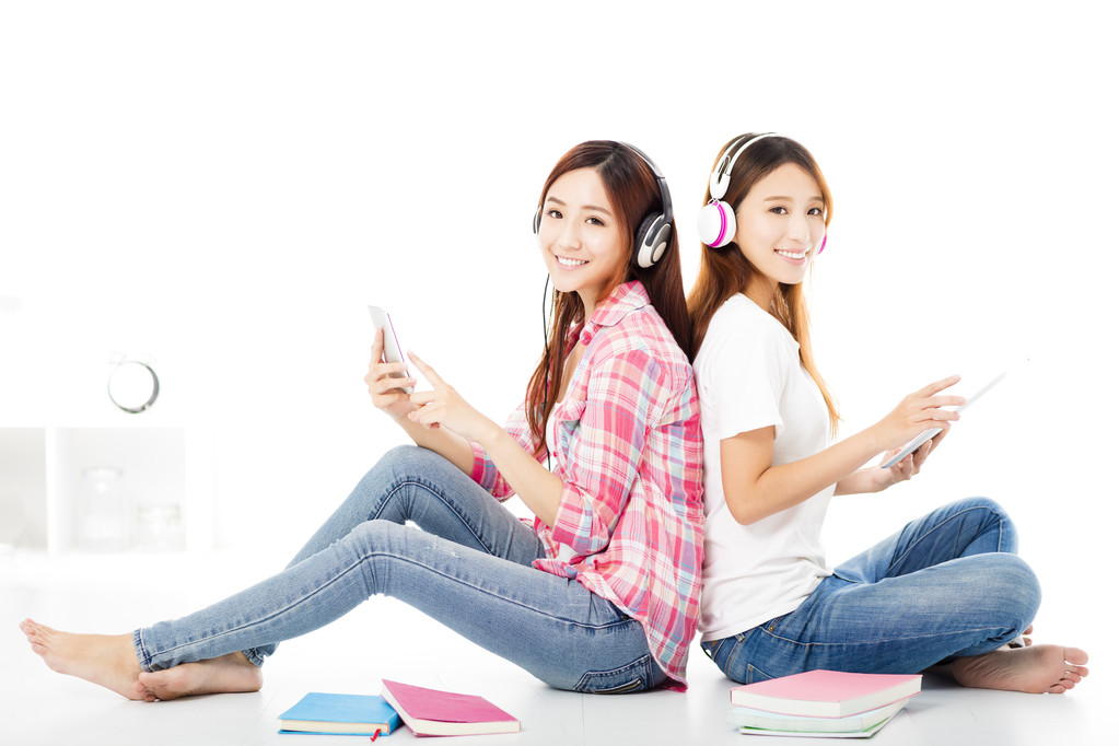 坐在地板上的两个快乐的青少年学生女孩 坐在地板上的两个快乐的青少年学生女孩