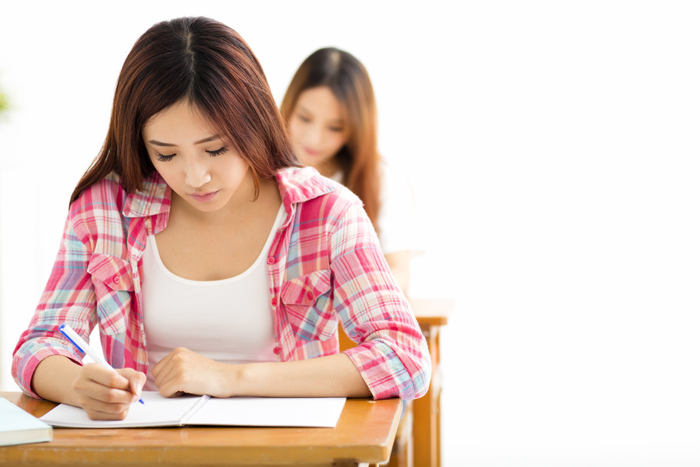 与其他年轻的学生在教室里写作笔记