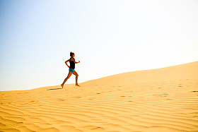 年轻女子在沙漠沙丘上运行图片