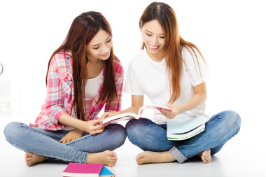 看著書的兩個快樂的青少年學(xué)生女孩