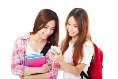 看著智能手機(jī)的兩個(gè)快樂的青少年學(xué)生女孩