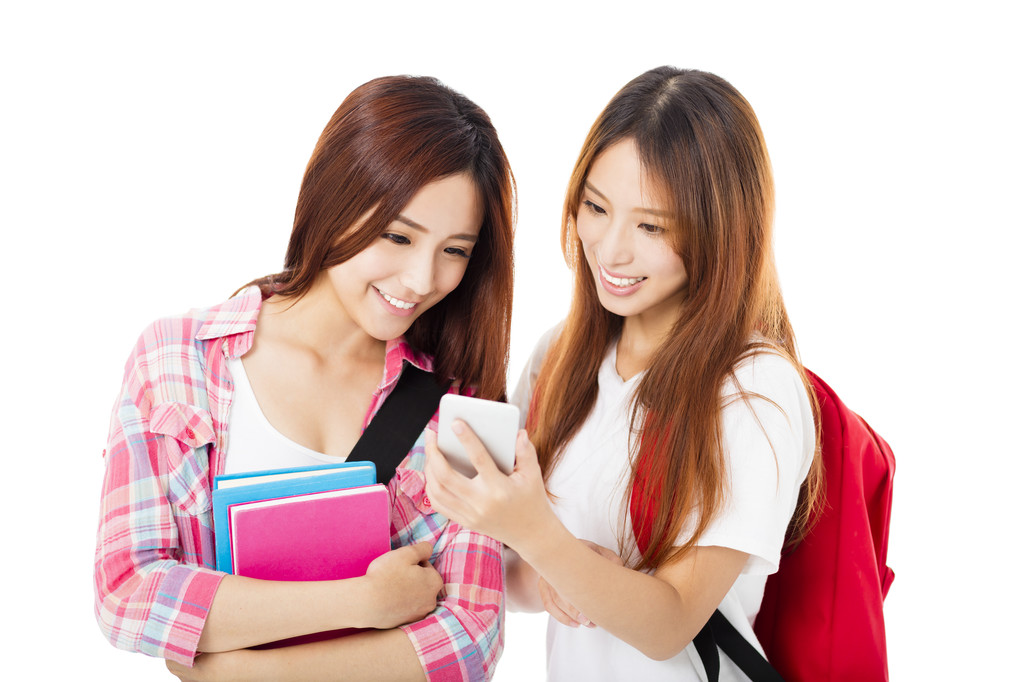 看着智能手机的两个快乐的青少年学生女孩 看着智能手机的两个快乐的青少年学生女孩